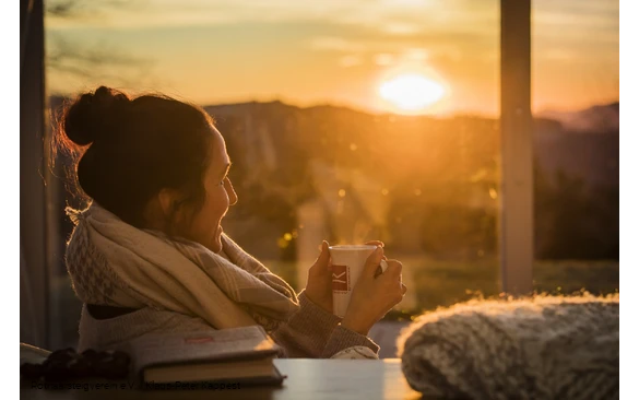 Frau mit Rothaarsteig-Tasse schaut in den Sonnenuntergang