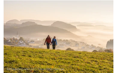 Zwei Wanderer am Morgen mit Ort im Hintergrund