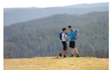 Zwei sportlich gekleidete Personen mit Speed Hiking-Ausrüstung vor einer Bergkulisse