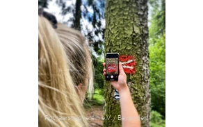 Wanderin fotografiert das Rothaarsteig-Logo mit einem Smartphone